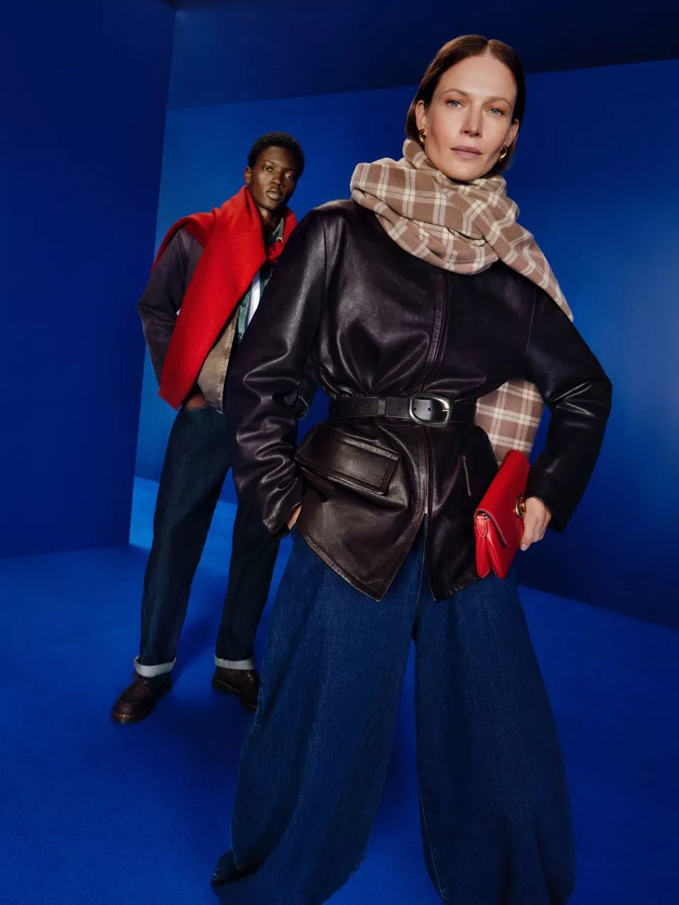a woman and man in leather coat and jeans in blue studio backdrop