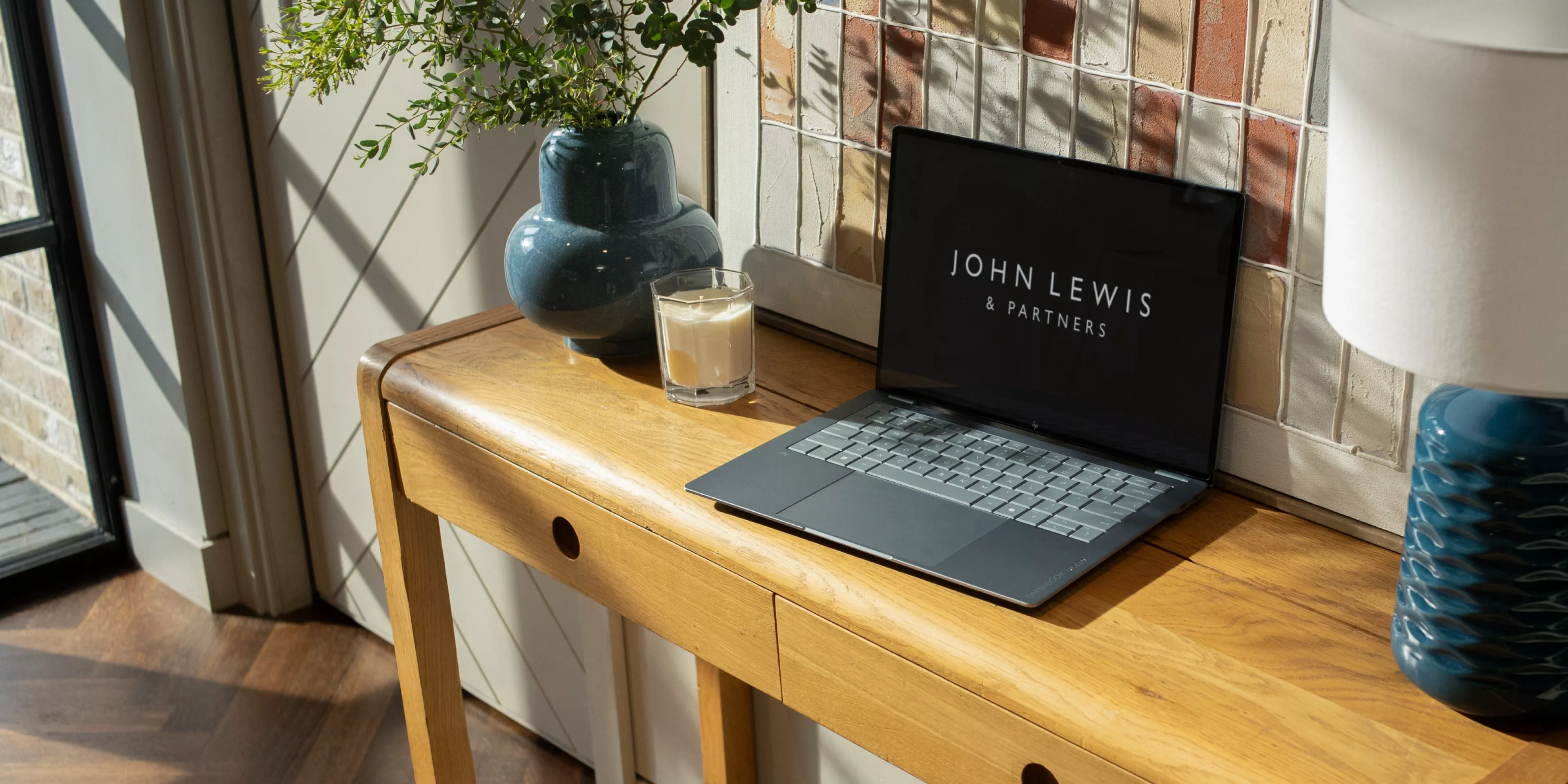 Laptop with large bezel-less display and webcam, showing abstract wallpaper on a desk, close-up view