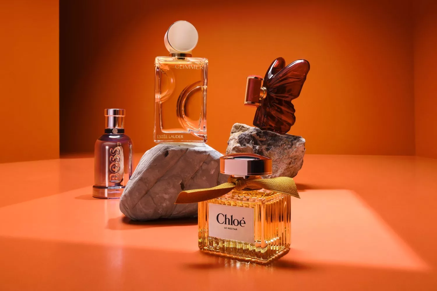 Miu Miu perfume bottle and Gucci Bloom Ambrosia d’Oro fragrance box on a blue surface by the sea backdrop