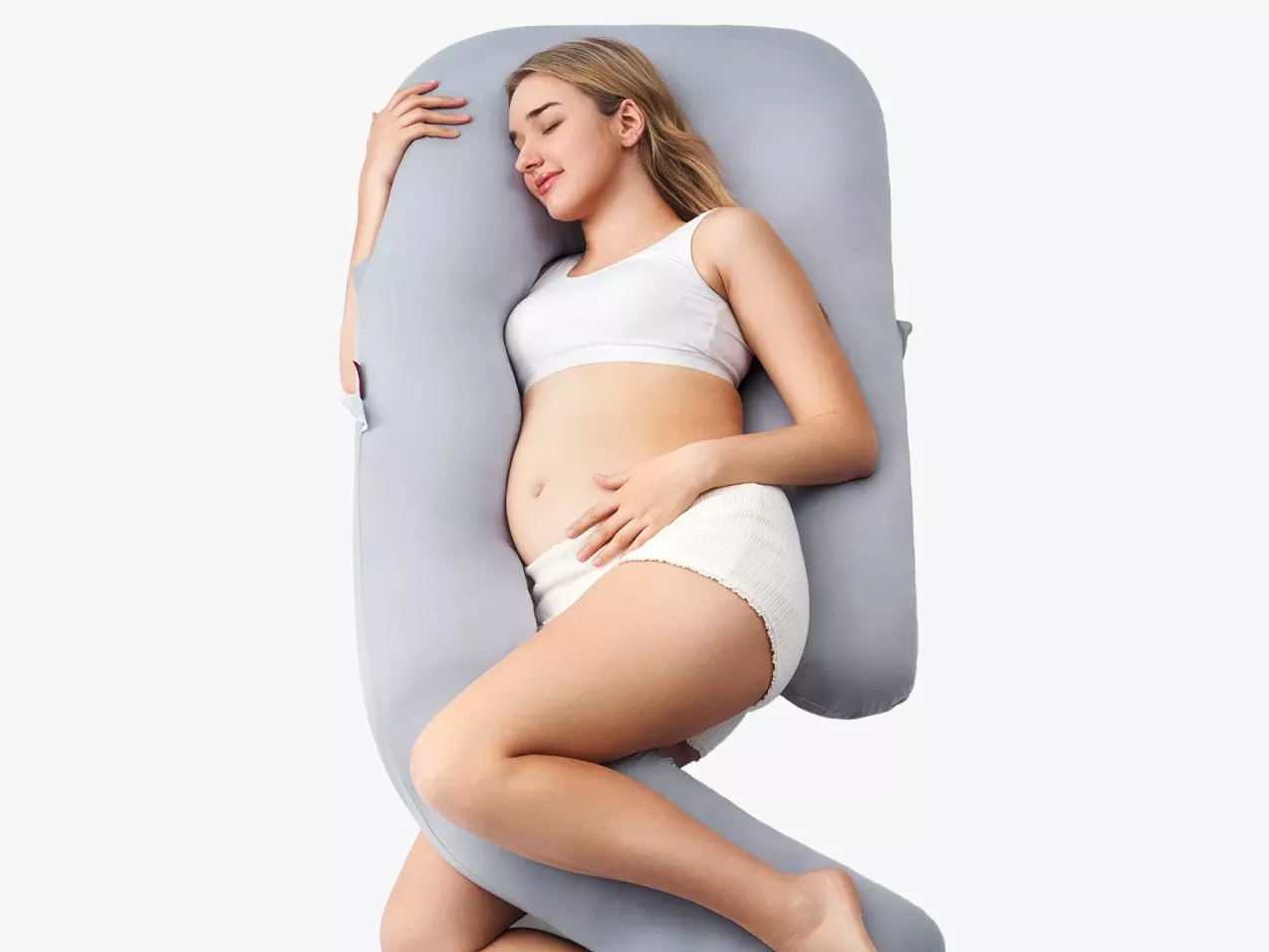 Pregnant woman sleeping on grey U-shaped maternity pillow for side support and comfortable pregnancy rest