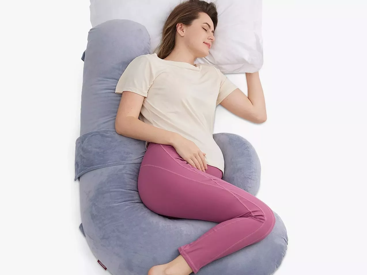 Woman sleeping on grey full-body pregnancy pillow for side sleepers, supporting back, hips and legs