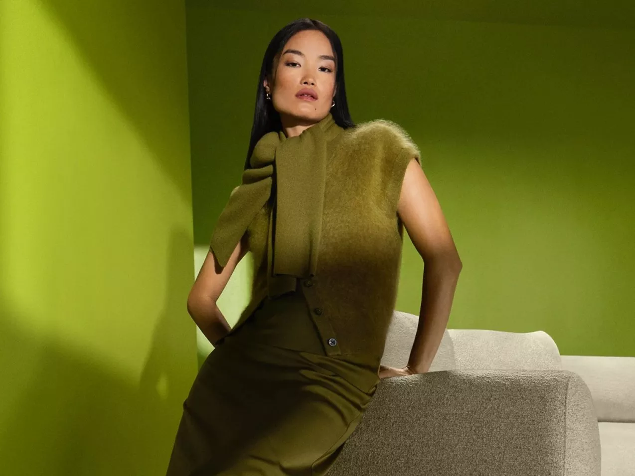 a model sitting on a chair wearing a brown faux fur coat