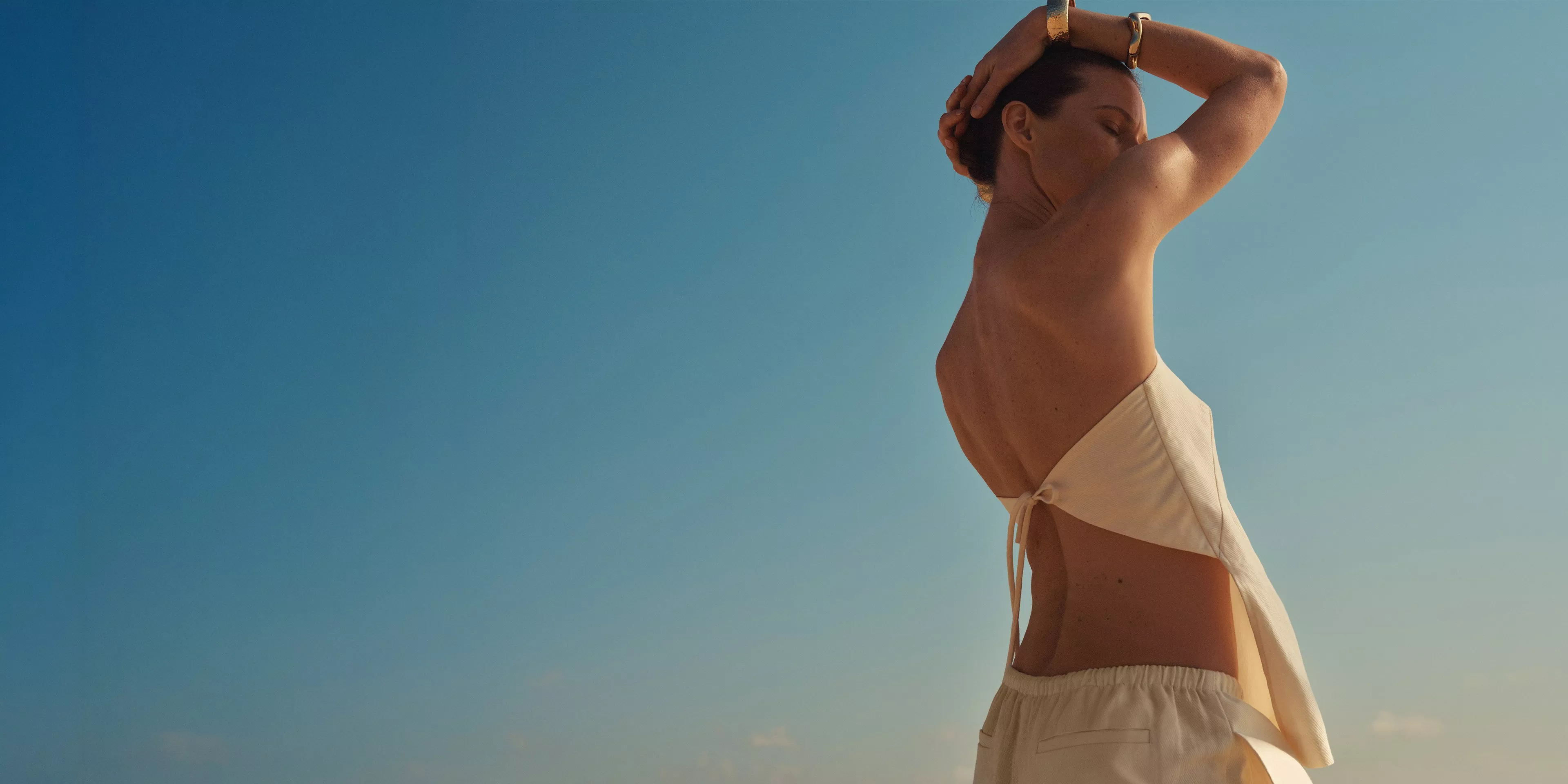Lady standing in the sun with a white top and trousers on