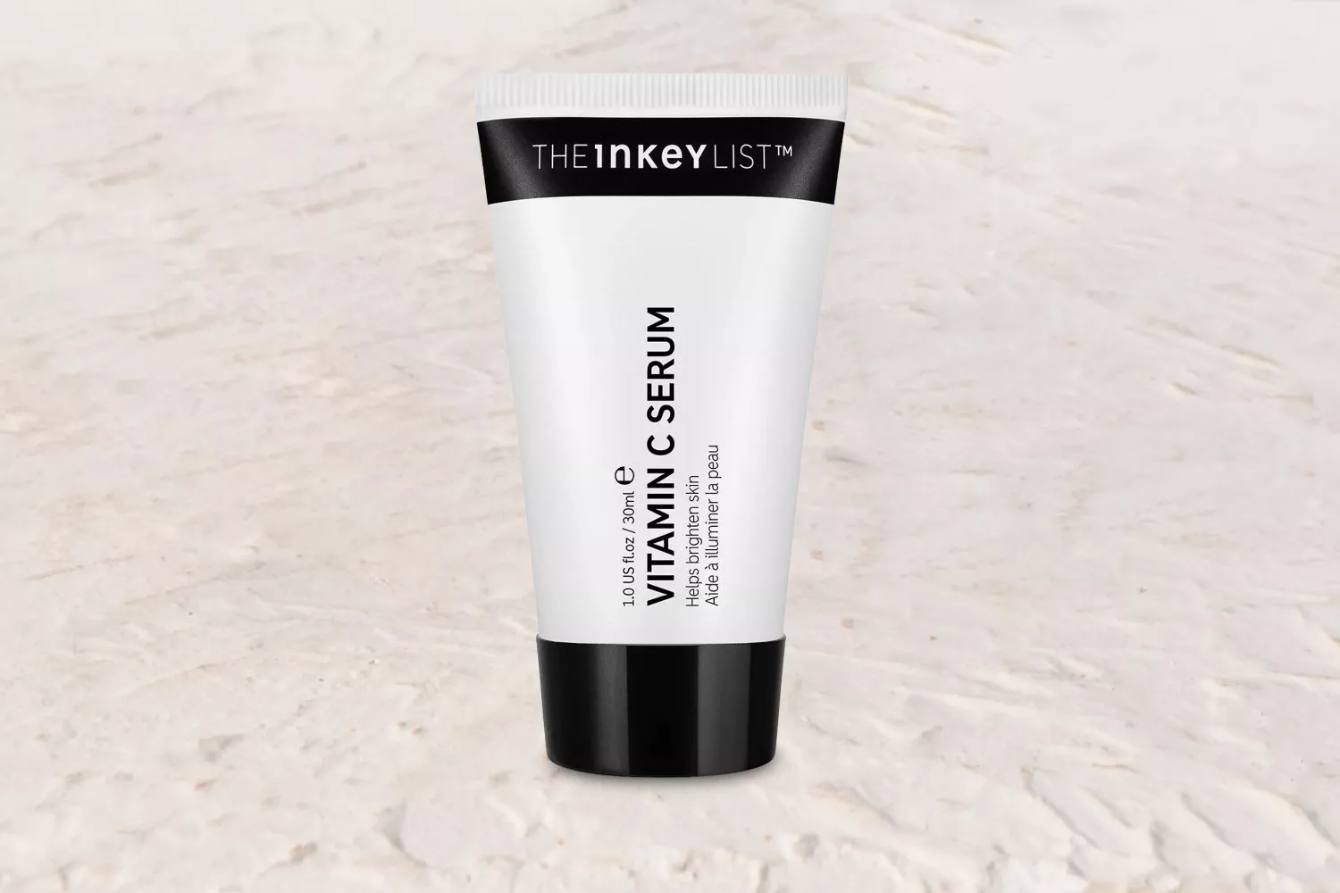 The Inkey List Vitamin C Serum tube on a coastal backdrop, highlighting skincare and natural beauty.