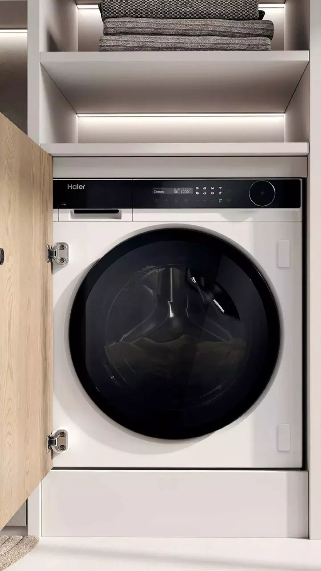 Built-in Haier front-loading washing machine in modern laundry cupboard with shelves and LED strip lighting