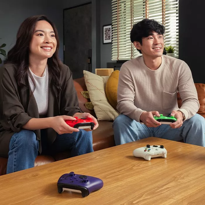 Gamer playing racing game on large 4K smart TV with ambient backlight, showing sports cars on track in living room