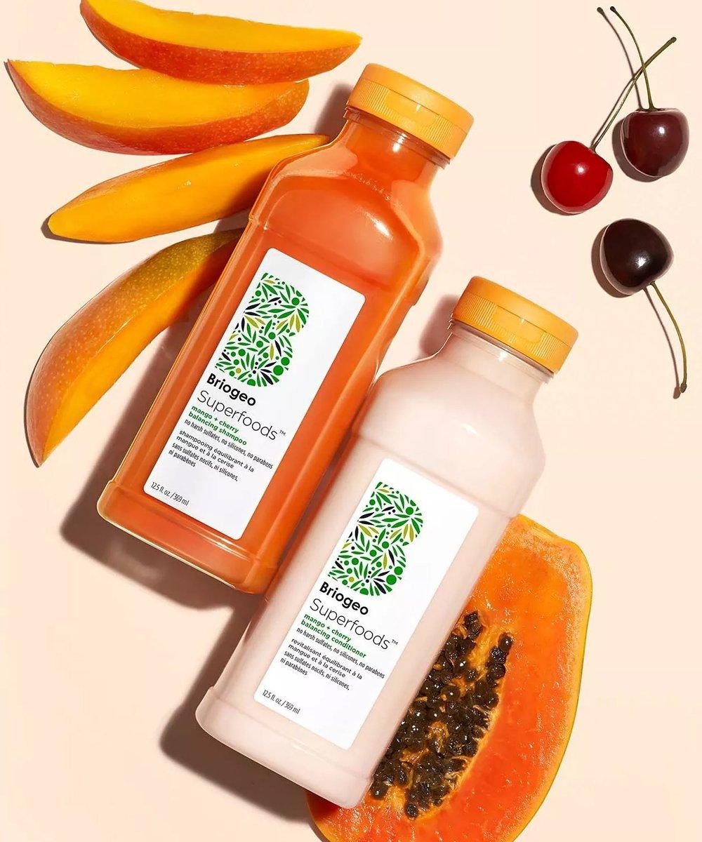 briogeo products on a orange background with papaya, mango and cherries