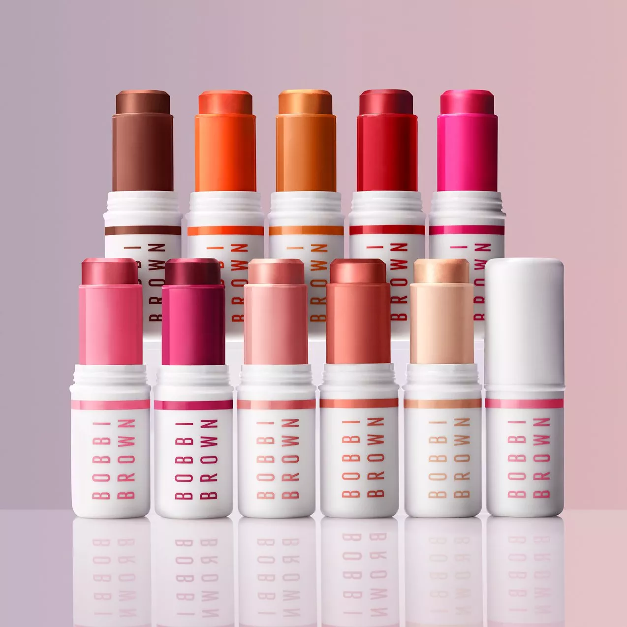 A collection of Bobbi Brown lipsticks in various vibrant shades, displayed on a reflective surface.
