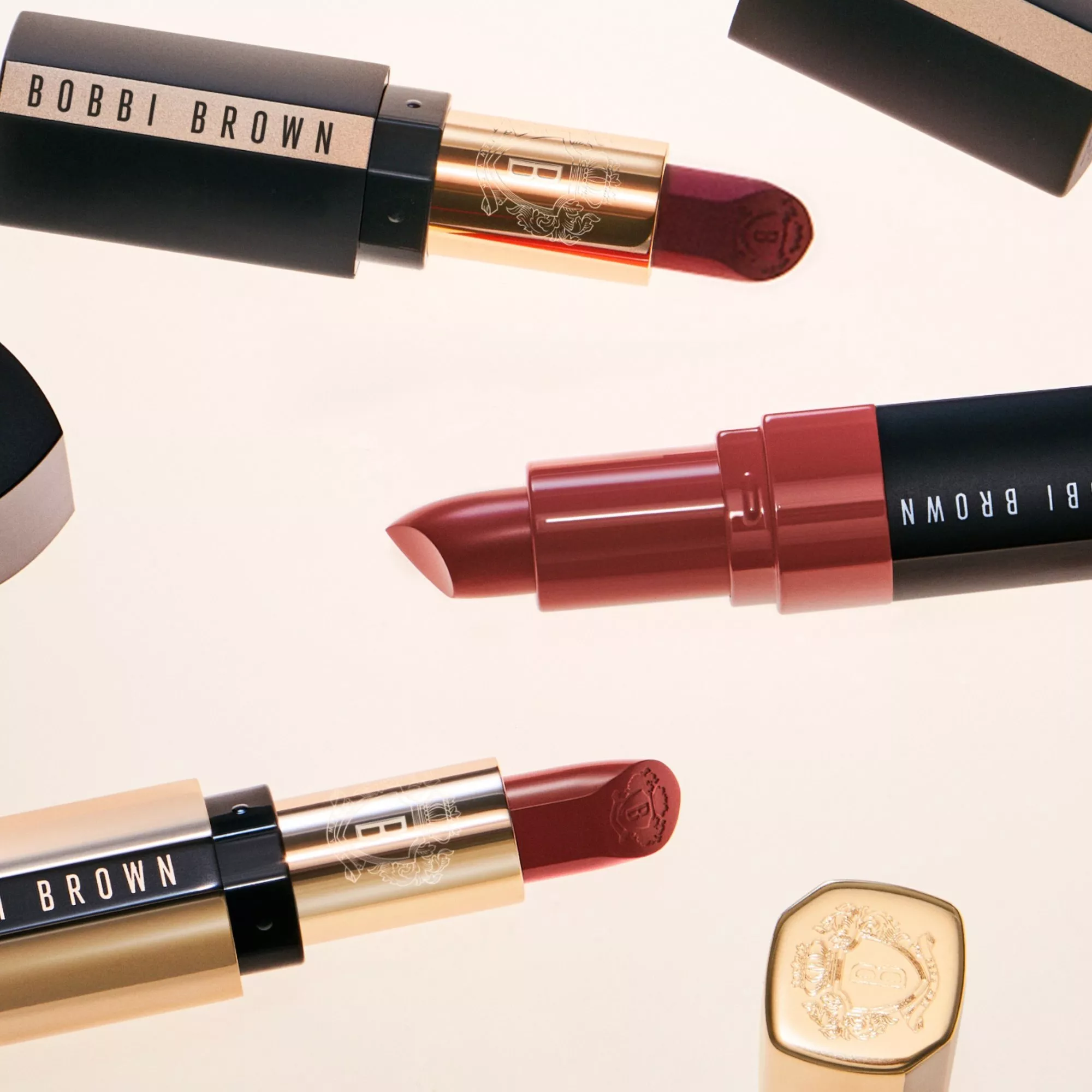 Bobbi Brown lipstick collection in nude and berry shades, open tubes on a clean white background flat lay