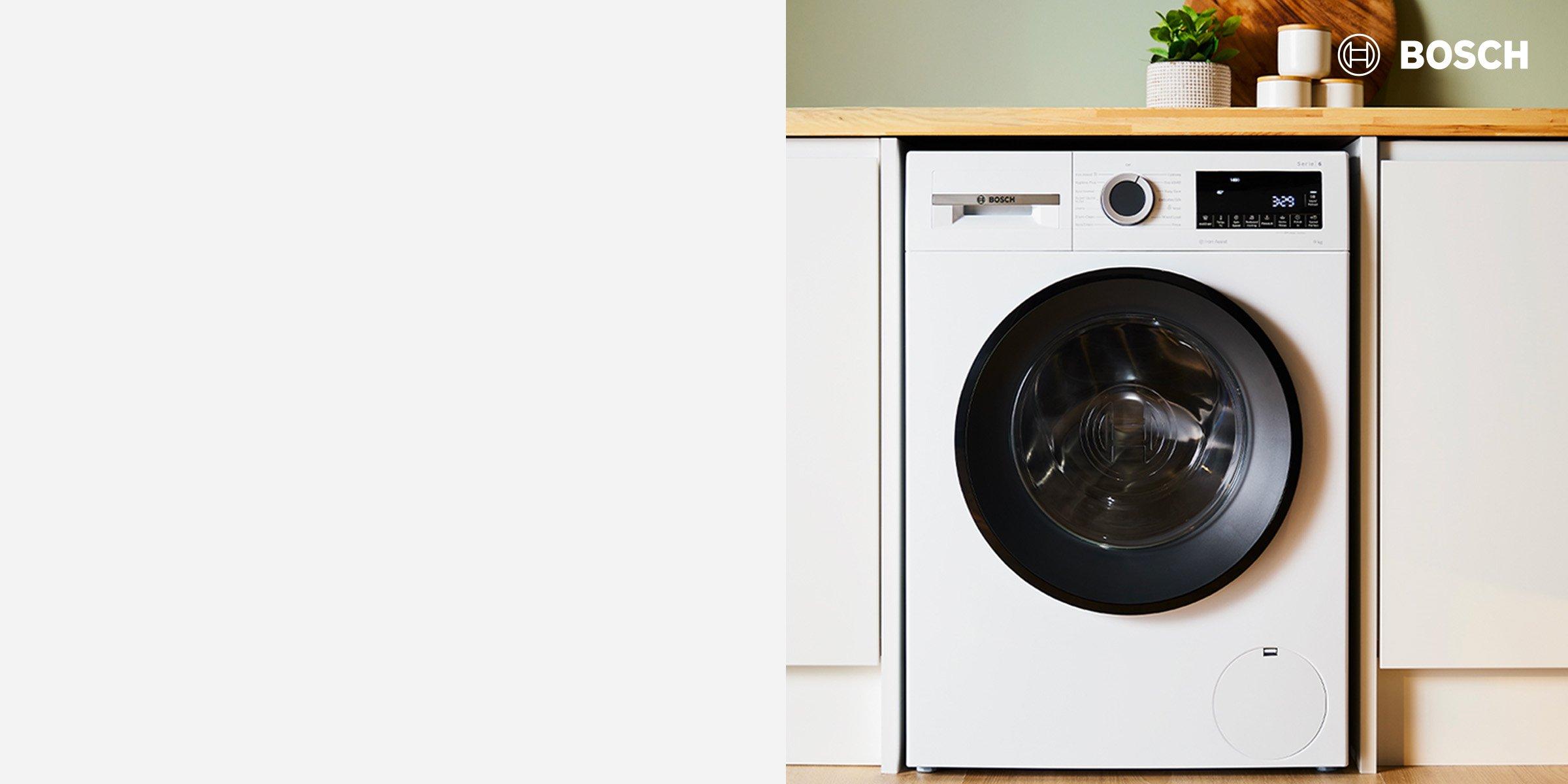 Miele washing machine on the floor in the cabinet with towel and detergent