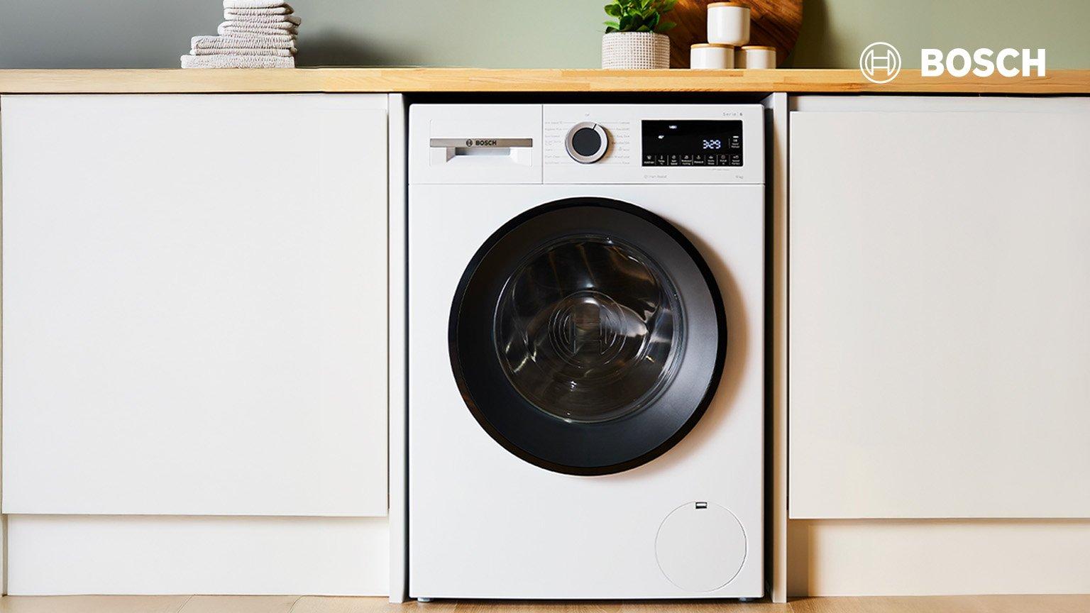 miele washing machine on the floor in the cabinet with towel and detergent