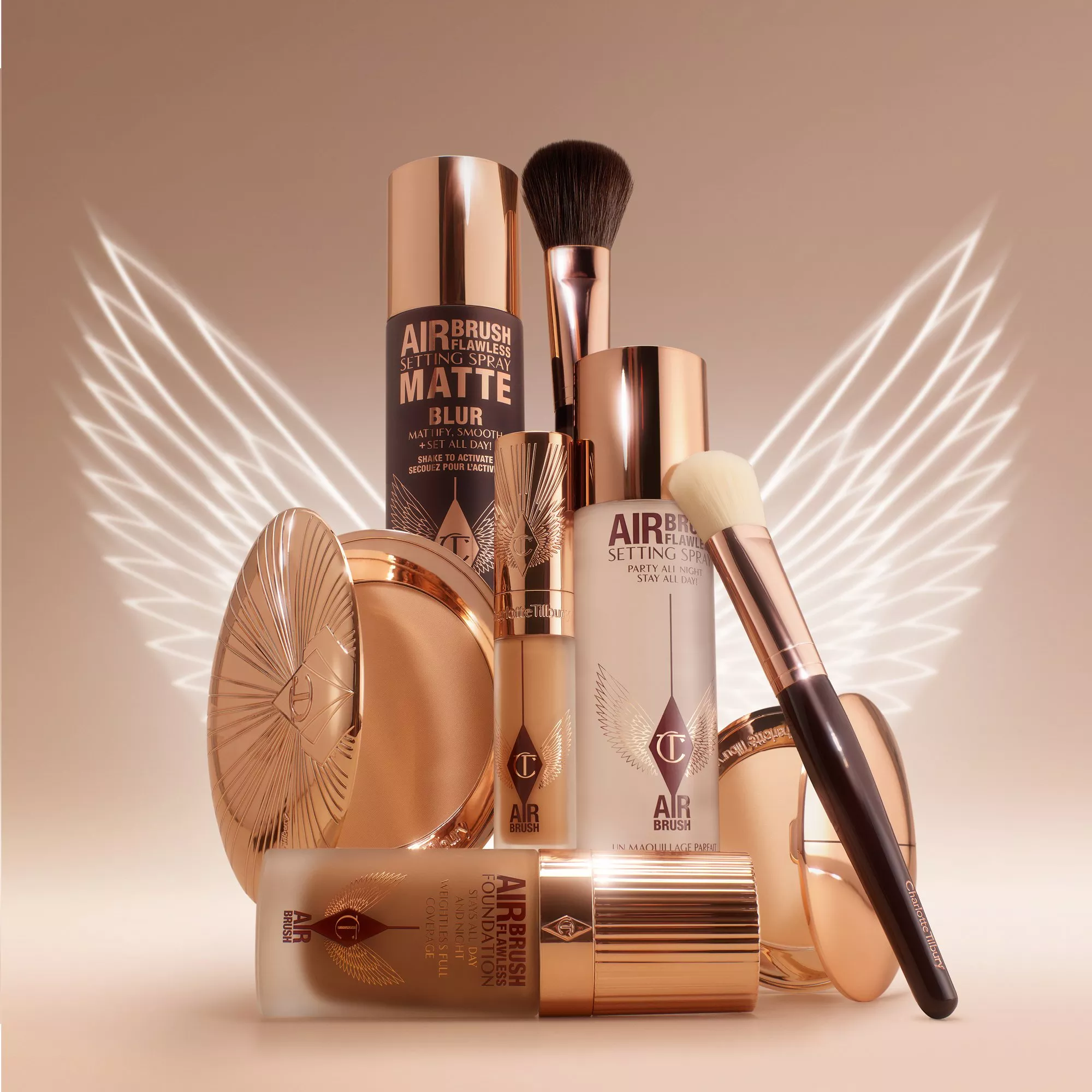 Luxury makeup collection with bronze and gold packaging, featuring brushes and setting sprays with winged light effects.
