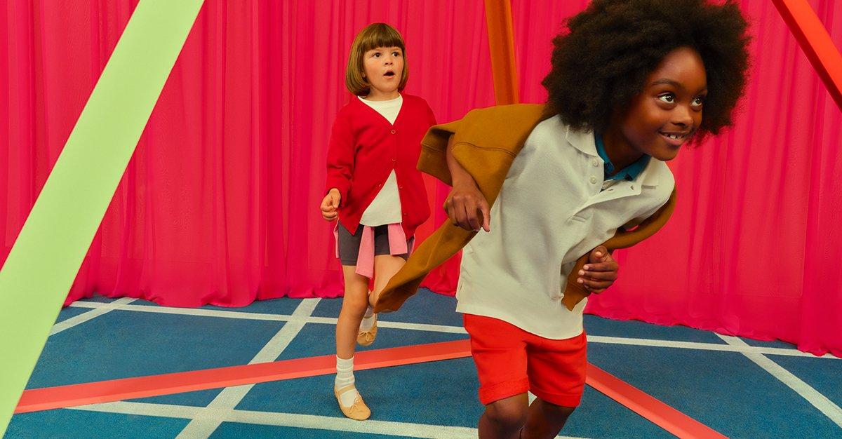 Two kids running and playing indoors with colorful geometric props.