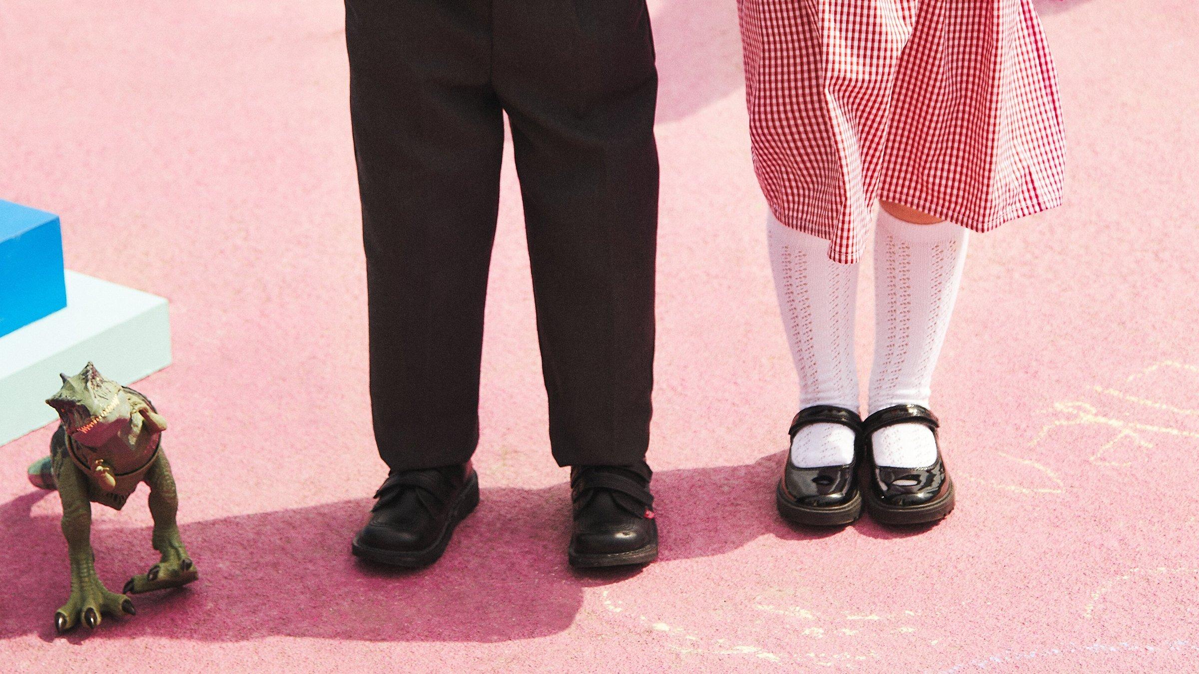 Close up image of two people wearing school shoes on the playground