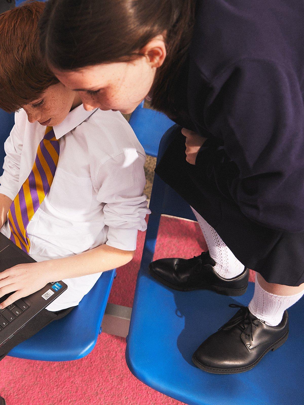 Close up image of two children with black school shoes