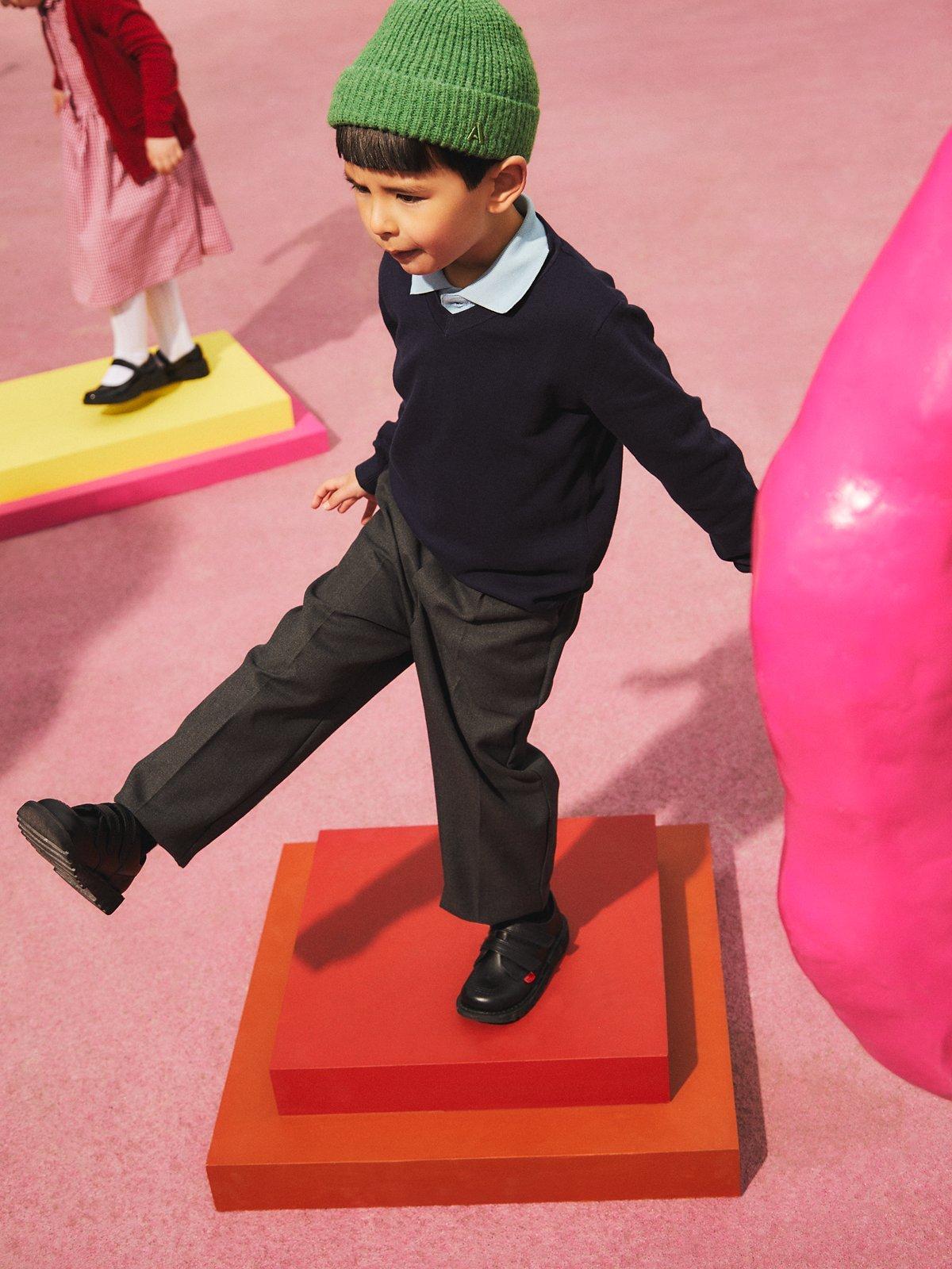 Image of a kid skipping through the playground with an green beanie hat on