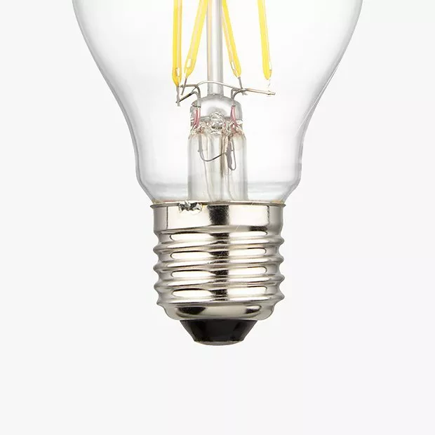 Clear glass light bulb with visible yellow filaments and silver screw base, against a plain background.