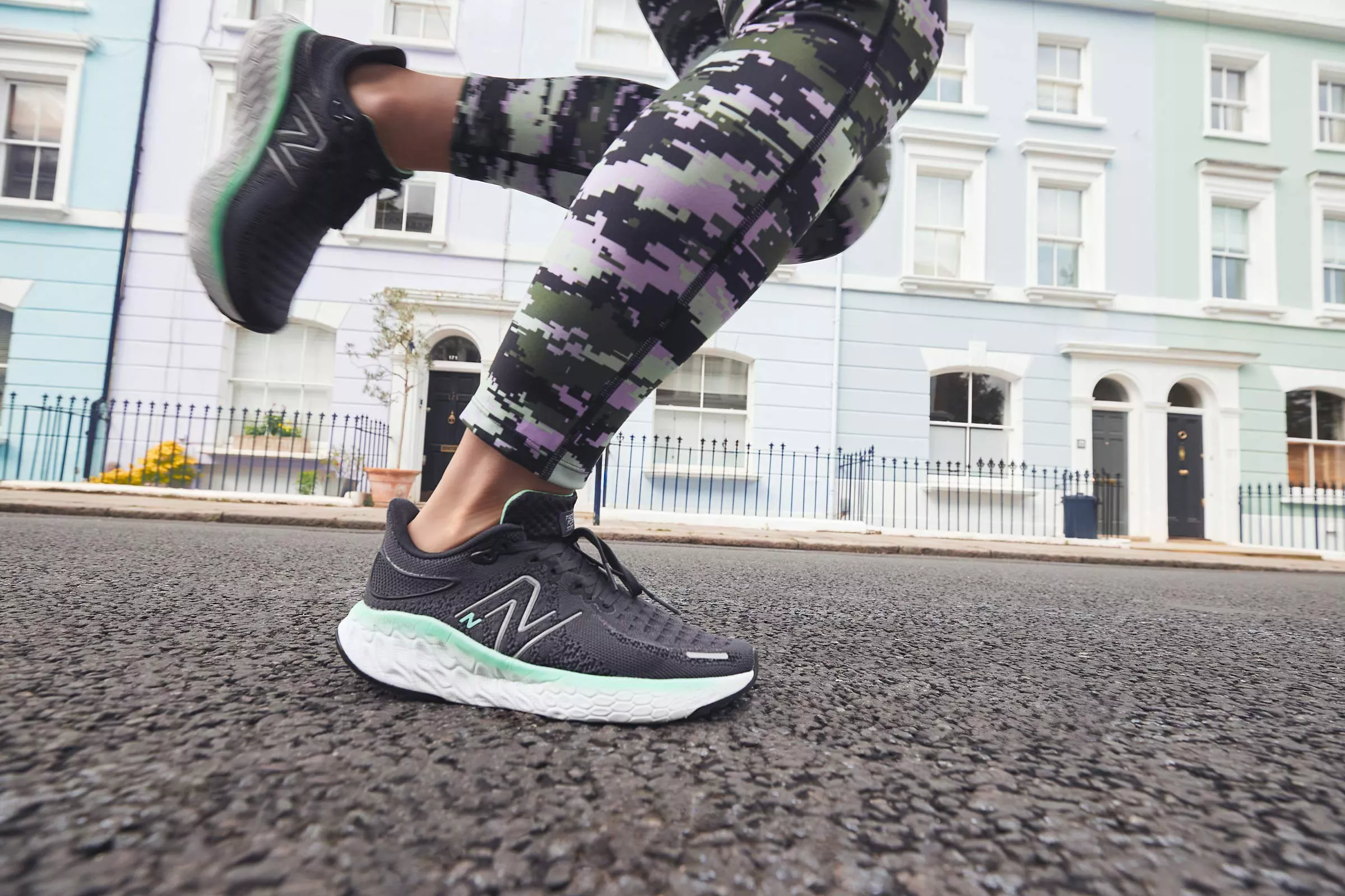 Close-up of runner wearing black trainers and camo leggings jogging on a residential street in the UK