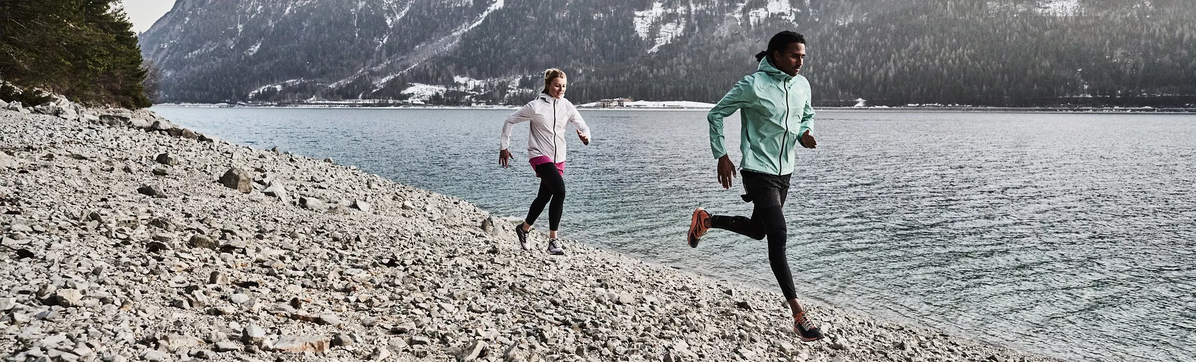 A man and women running on stones near the mountains
