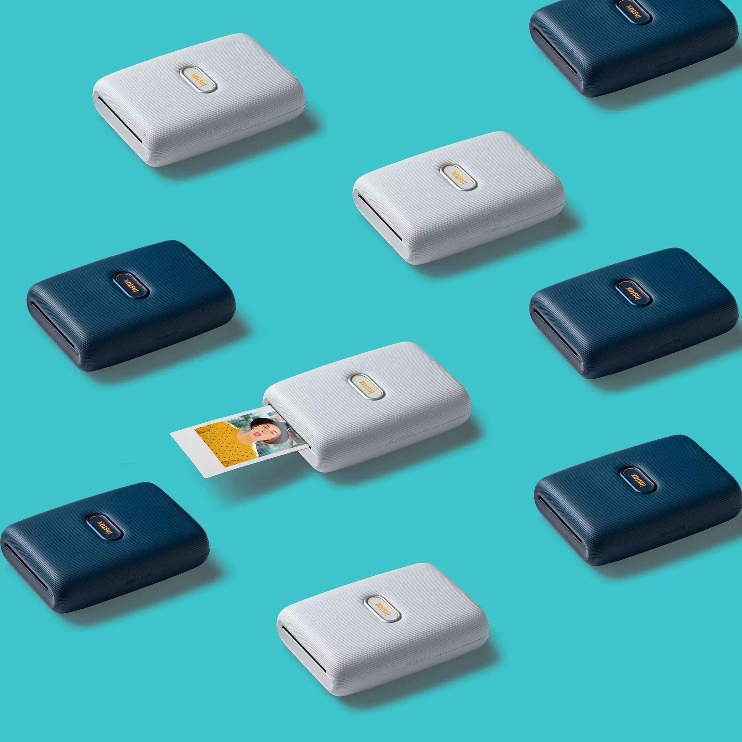 Portable photo printers in blue and white arranged on a turquoise background, with one printing an image.