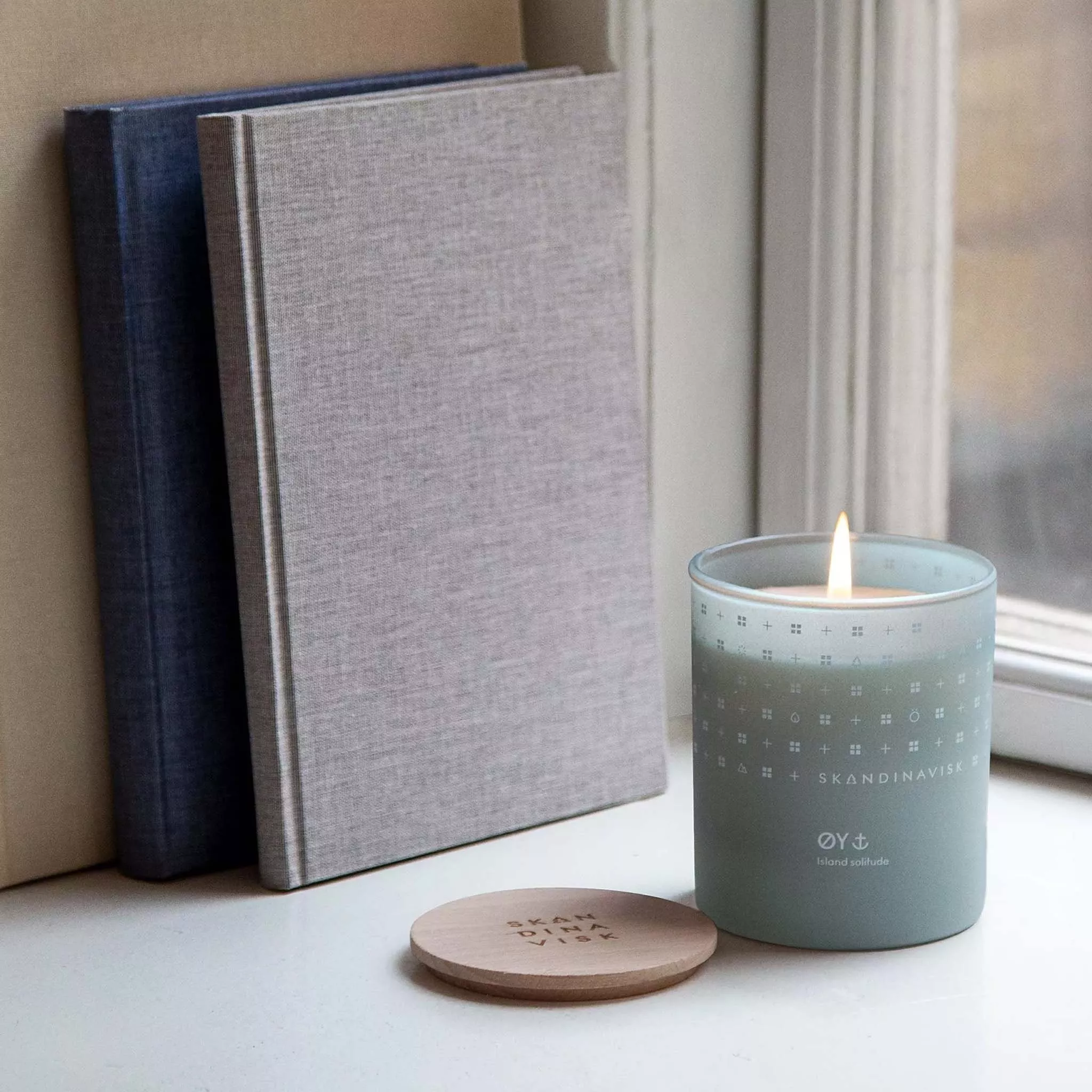 Blue candle lit next to some books