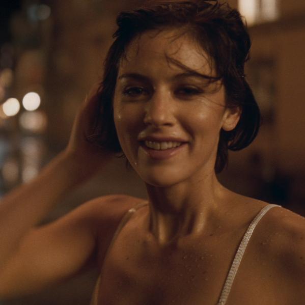 Close-up of smiling woman with wet hair in warm night lighting, cinematic portrait with soft bokeh background