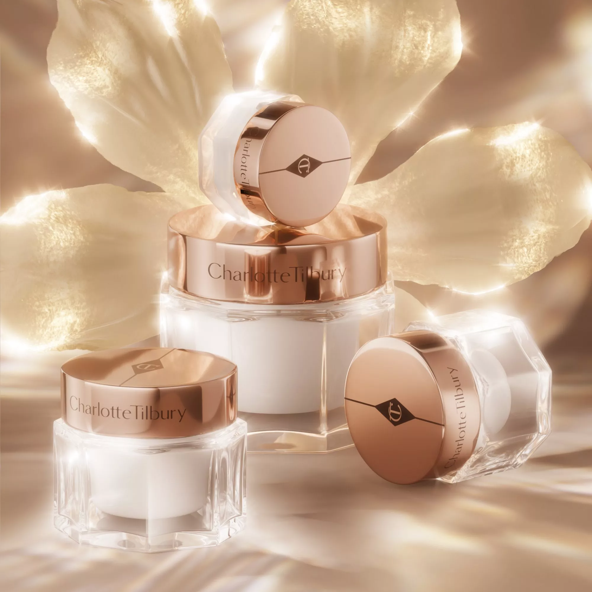 Luxurious Charlotte Tilbury skincare jars with rose gold lids, surrounded by glowing floral petals.