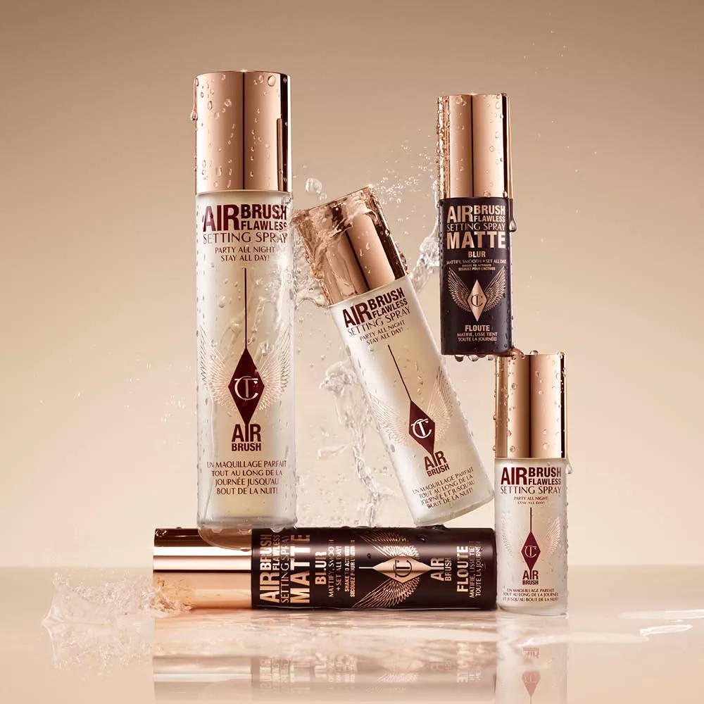 Luxury setting sprays with rose gold caps, elegantly arranged with water splashes on a beige background.