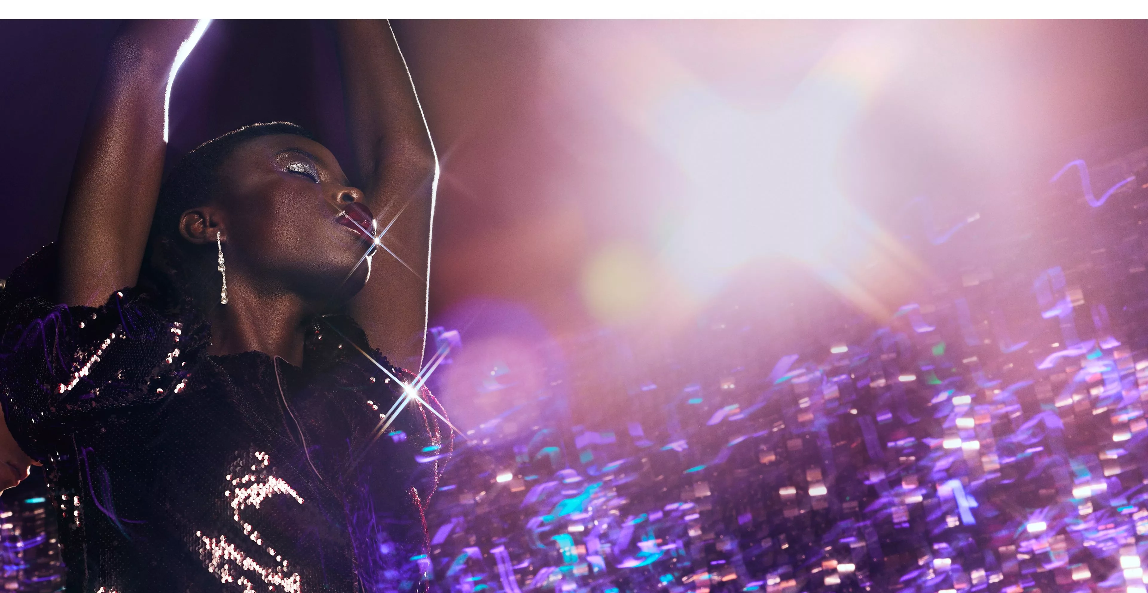Woman wearing sequinned top dancing in front of a disco backdrop