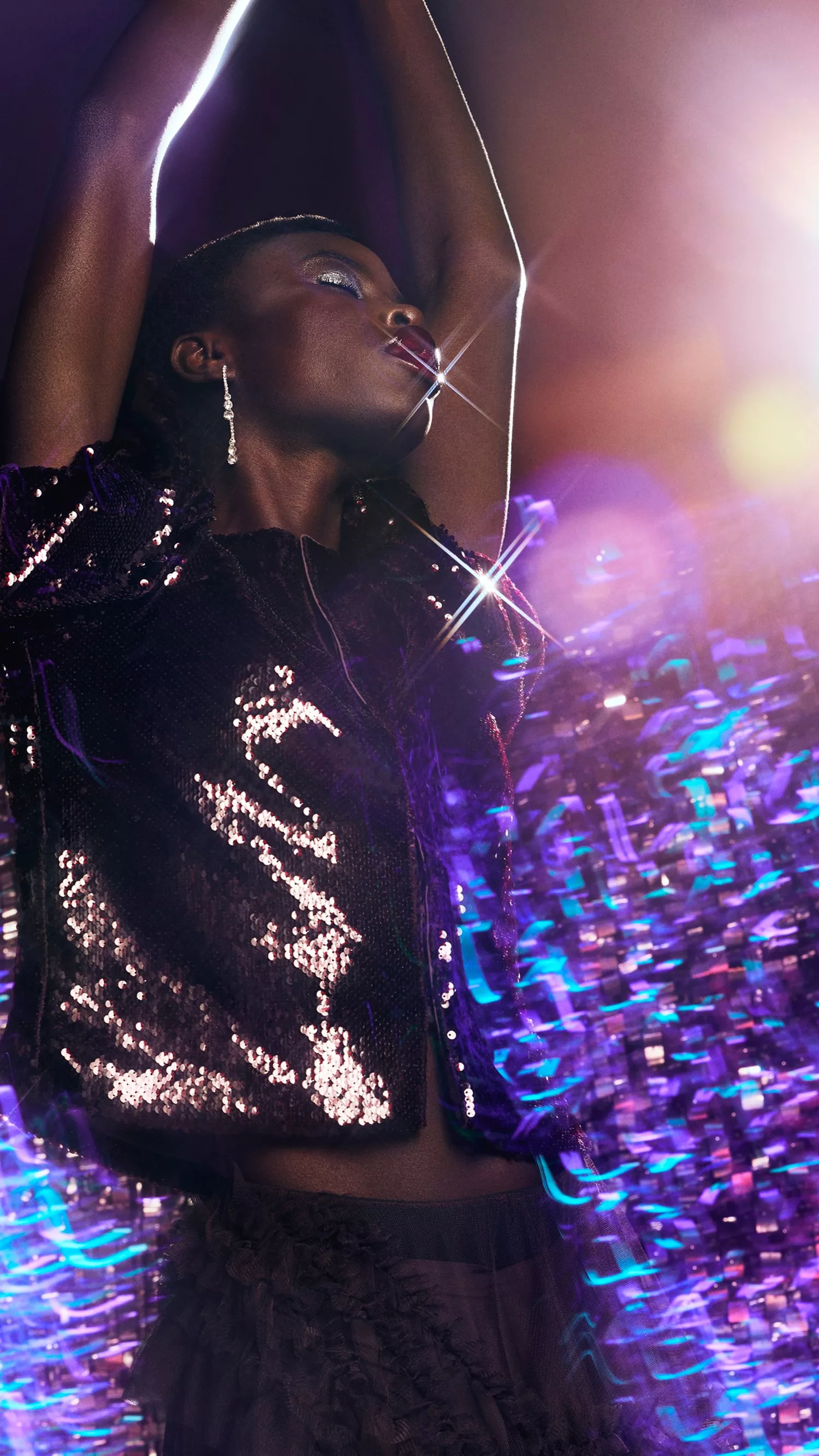 Woman wearing sequinned top dancing in front of a disco backdrop