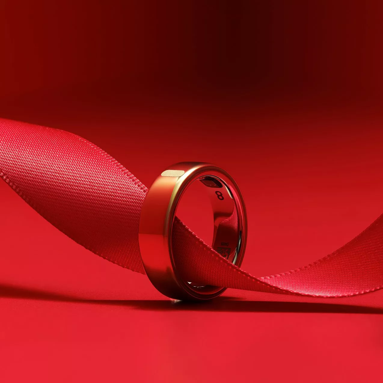 Oura ring with satin ribbon on red background, romantic jewellery product photo