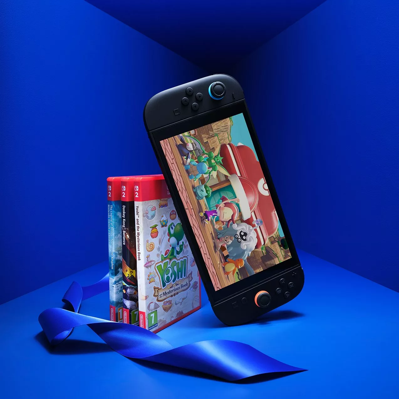 Nintendo Switch console with Yoshi game on screen, beside game cases and blue ribbon on blue background
