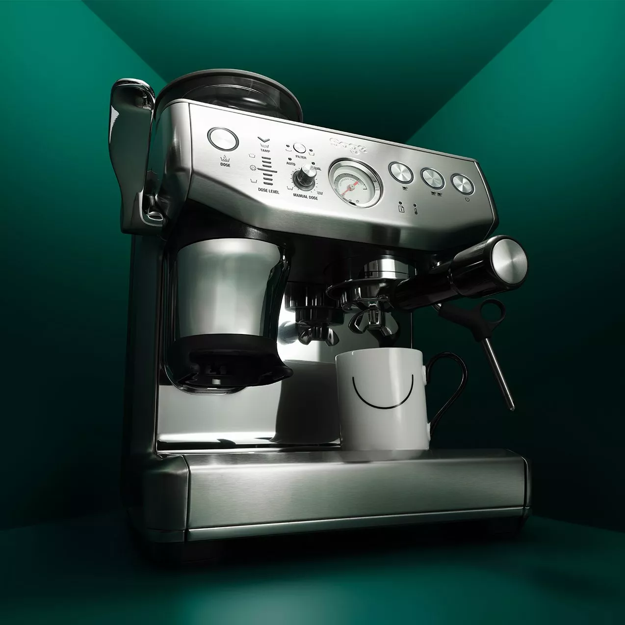 Stainless steel espresso machine with portafilter and steam wand, brewing coffee into a white mug on countertop.