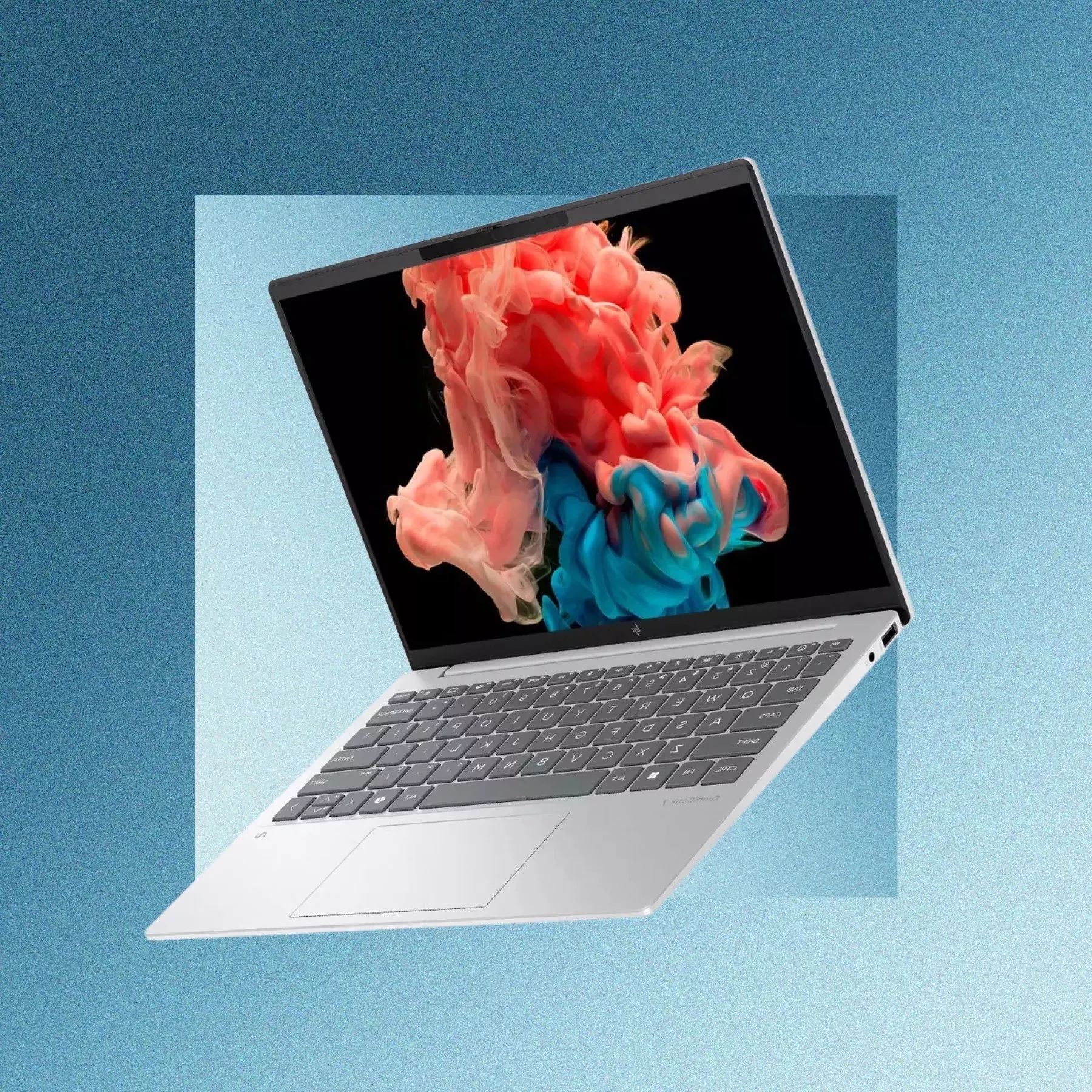 Silver ultra-slim laptop with vibrant red and blue abstract ink wallpaper on screen, on blue gradient background