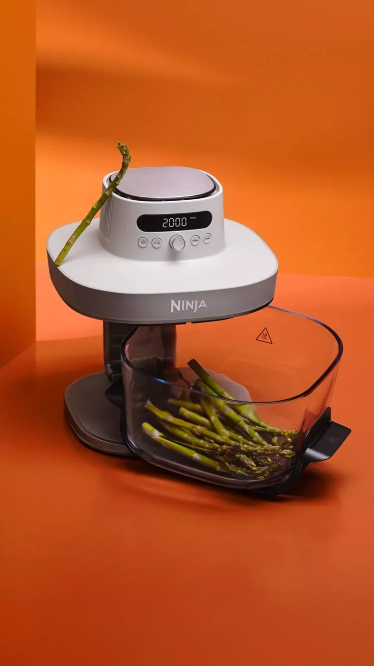 Ninja food processor with digital timer, chopping fresh asparagus spears in clear bowl on orange background