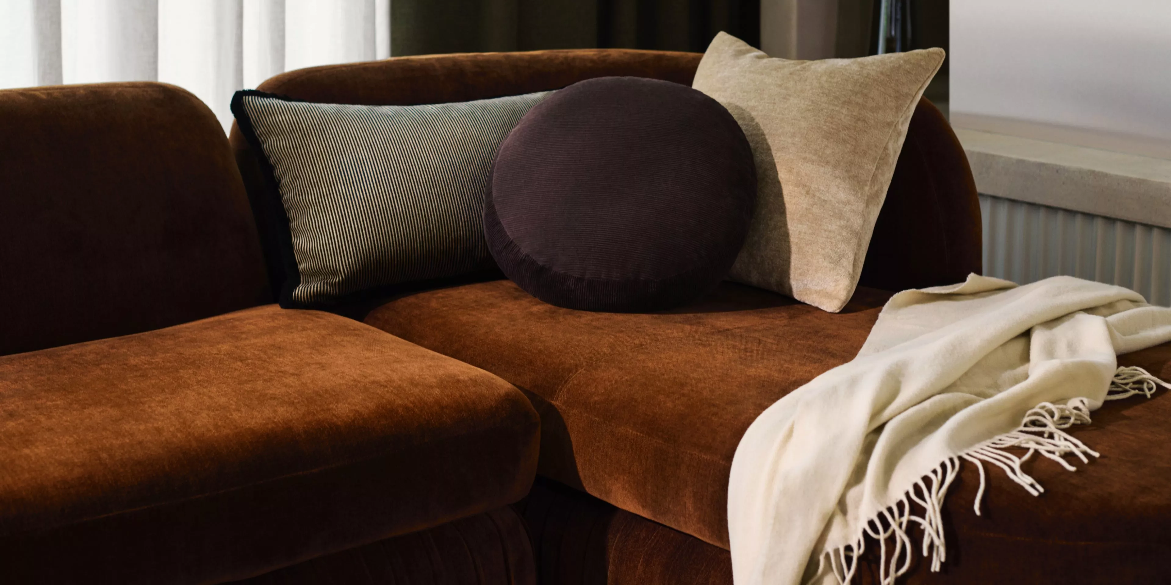 Burnt orange orange with scatter cushions and a blanket