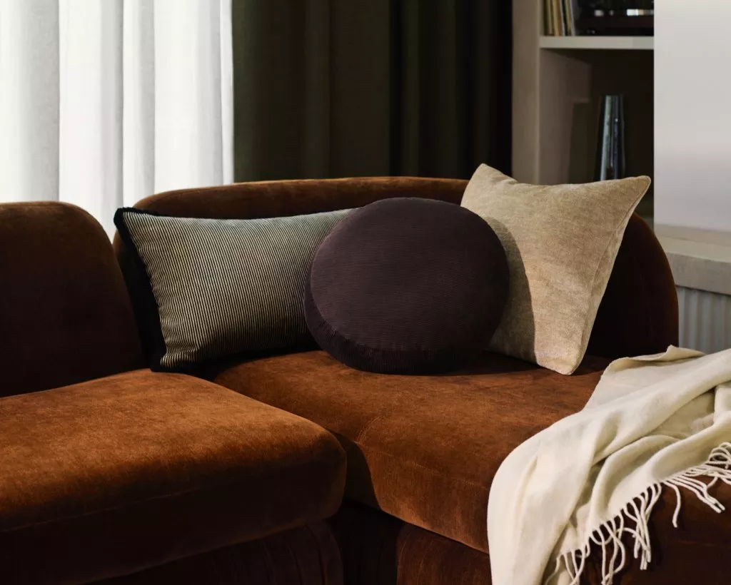 Burnt orange sofa with scatter cushions and blanket