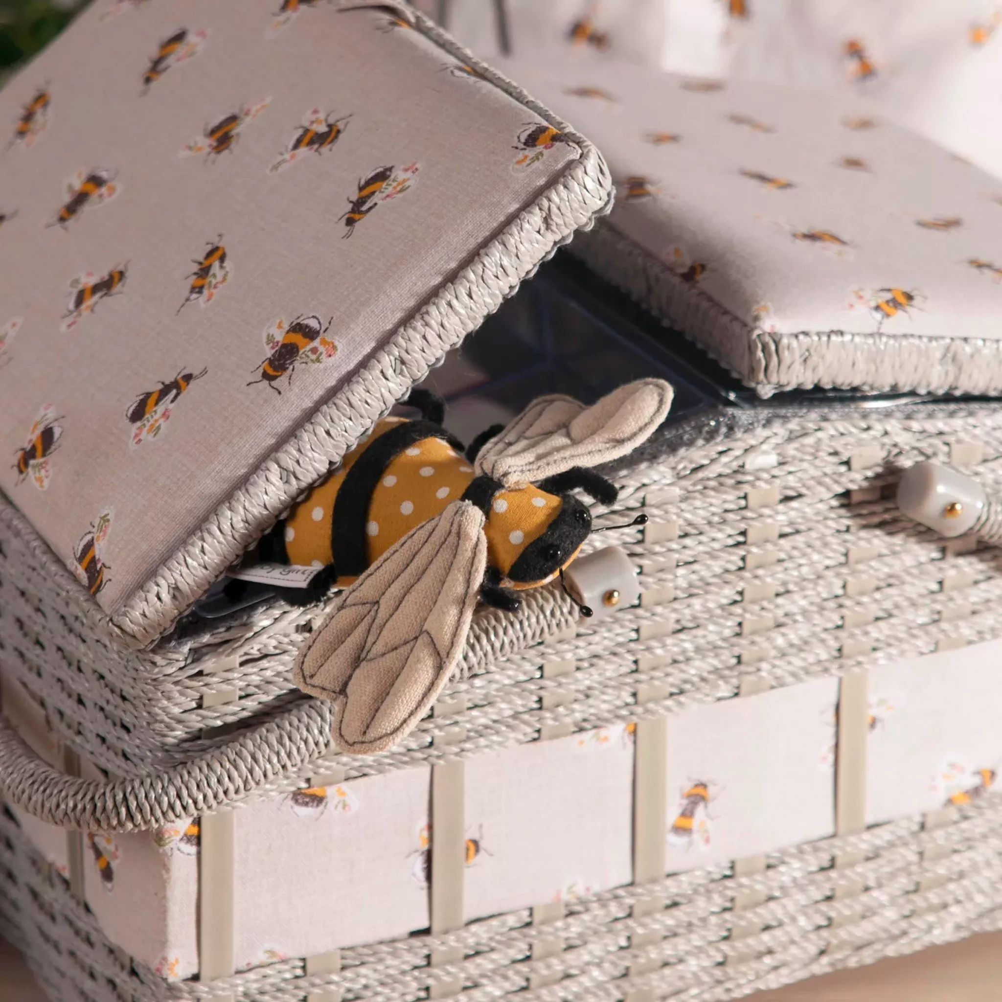 Grey wicker storage with bee pattern on the fabric detail
