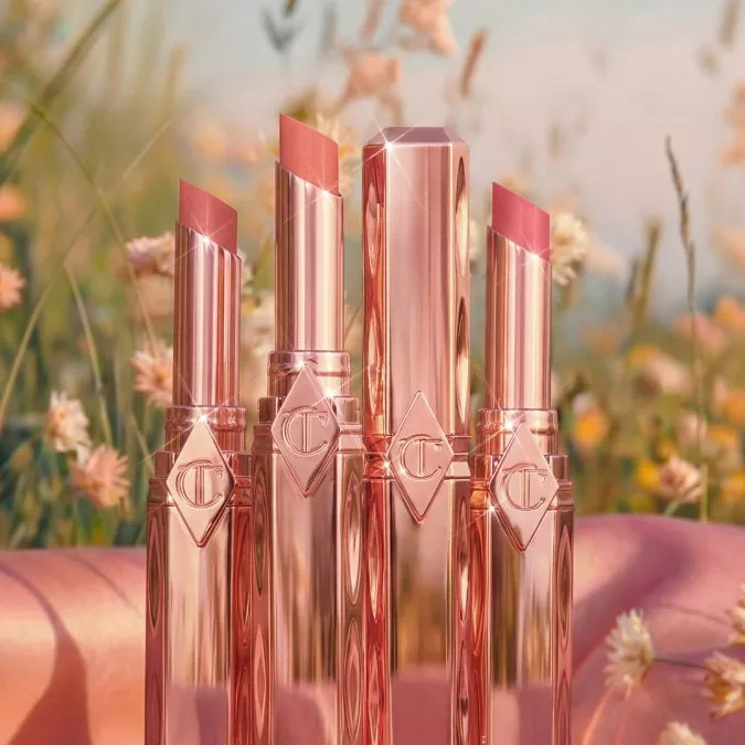 Gold compacts with intricately embossed floral makeup powders on a soft, light-reflecting surface.