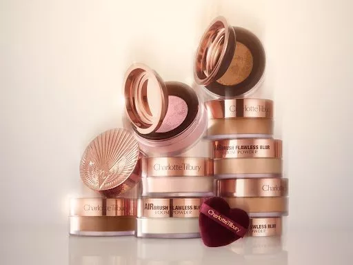 Charlotte Tilbury Airbrush Flawless Blur loose powder pots stacked with lids open on a soft beige background
