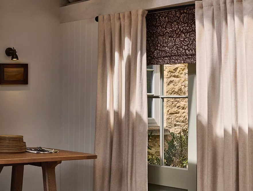 Door with beige curtains and a dark brown floral Roman blind on the window