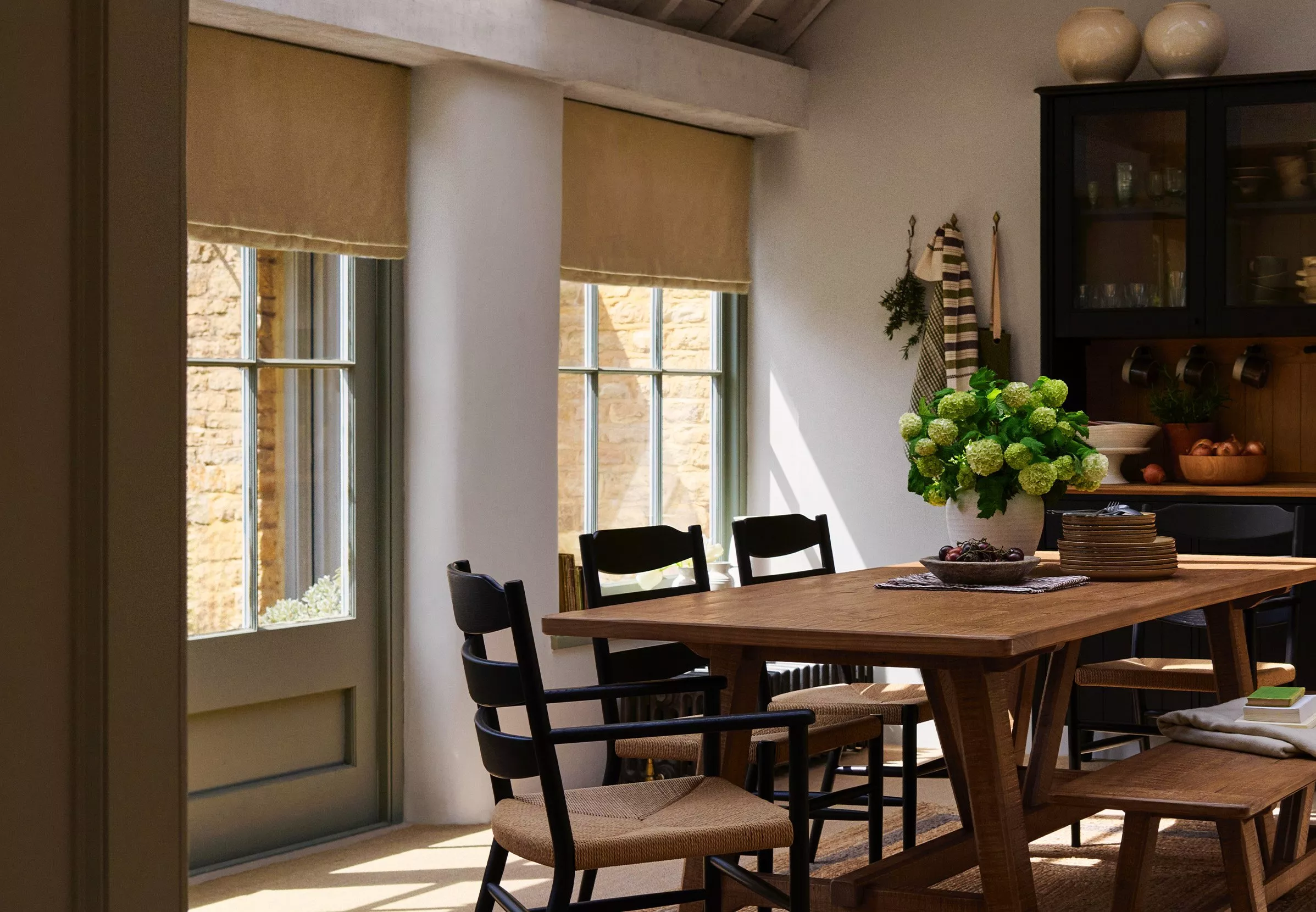 Dining room with wooden dining table and roman blinds on the window