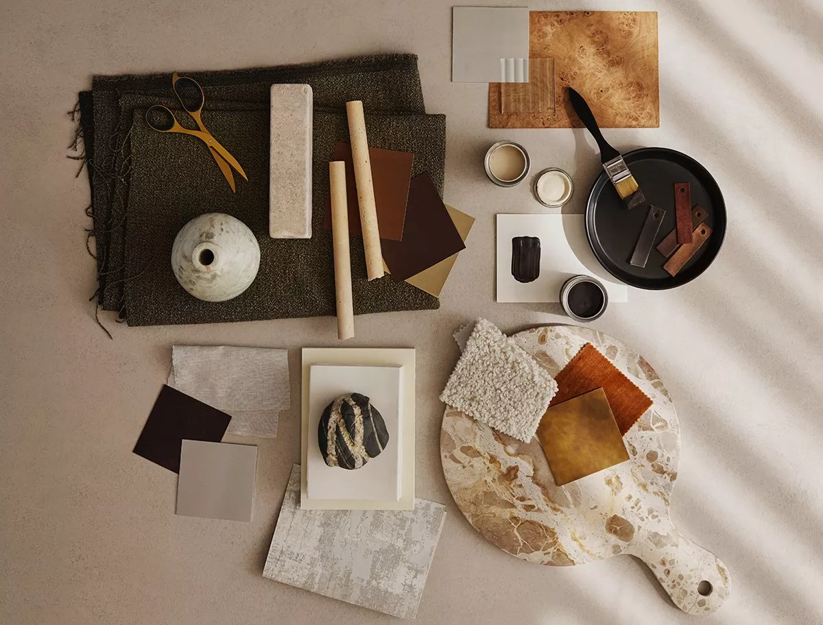 Table scattered with material swatches, scissors and a paint brush