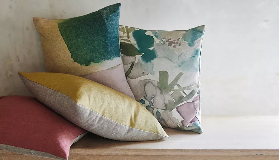 Colourful decorative cushions with abstract floral and colour-block designs on a wooden bench, modern home décor