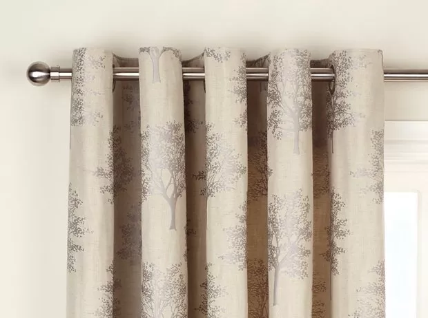 Neutral tree-pattern pencil pleat curtains on a chrome pole, styled for modern living room window décor