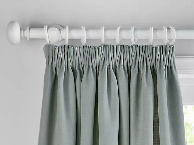 Grey pencil pleat curtains on a white curtain pole with rings, close-up of modern window dressing detail