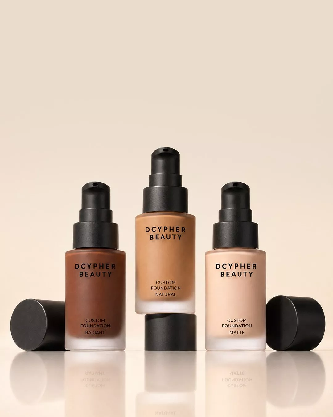 DCYPHER Beauty custom foundation bottles in radiant, natural and matte finishes on a beige studio backdrop