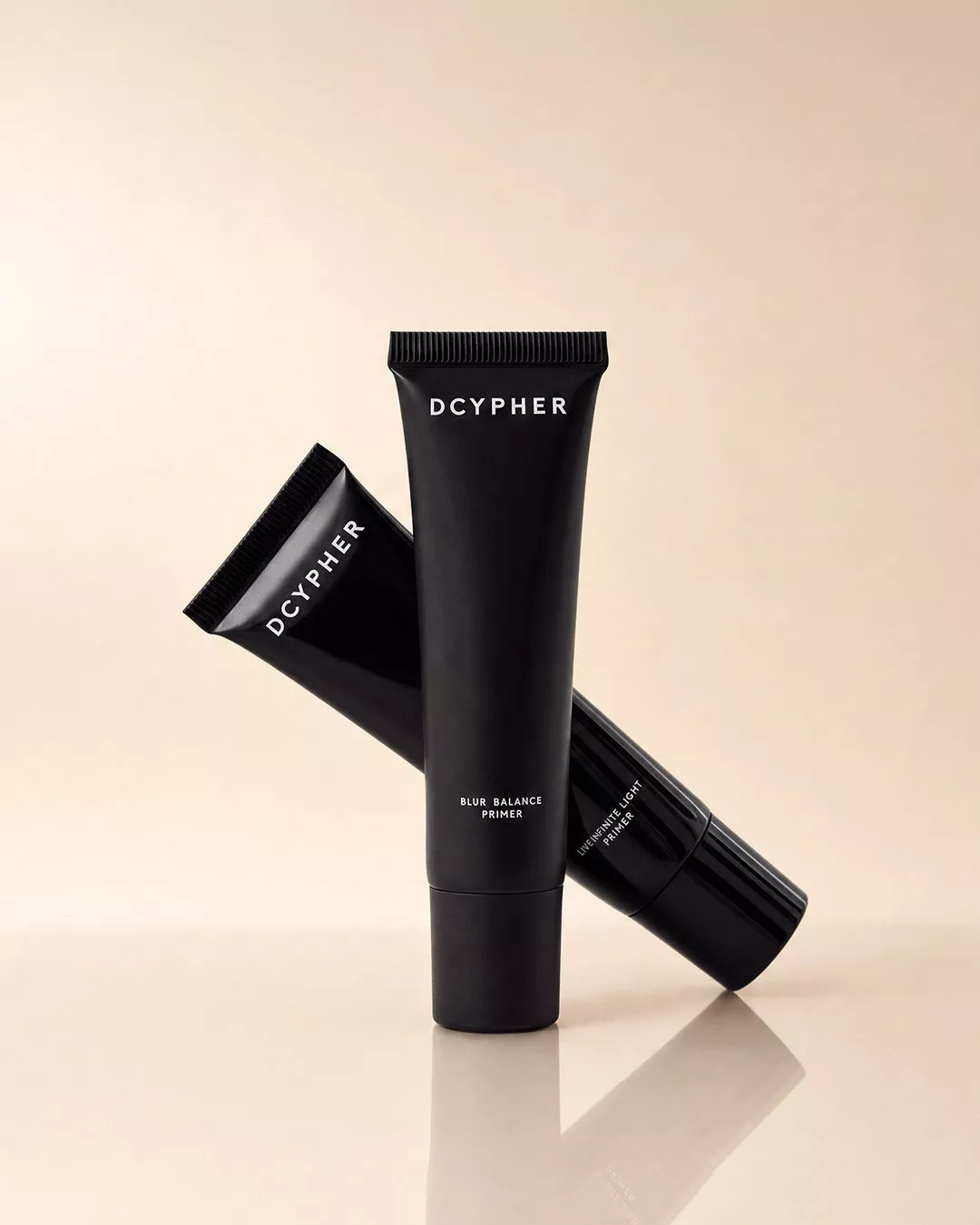 DCYPHER Blur Balance Primer tubes in black packaging, studio product shot on a beige background with reflection