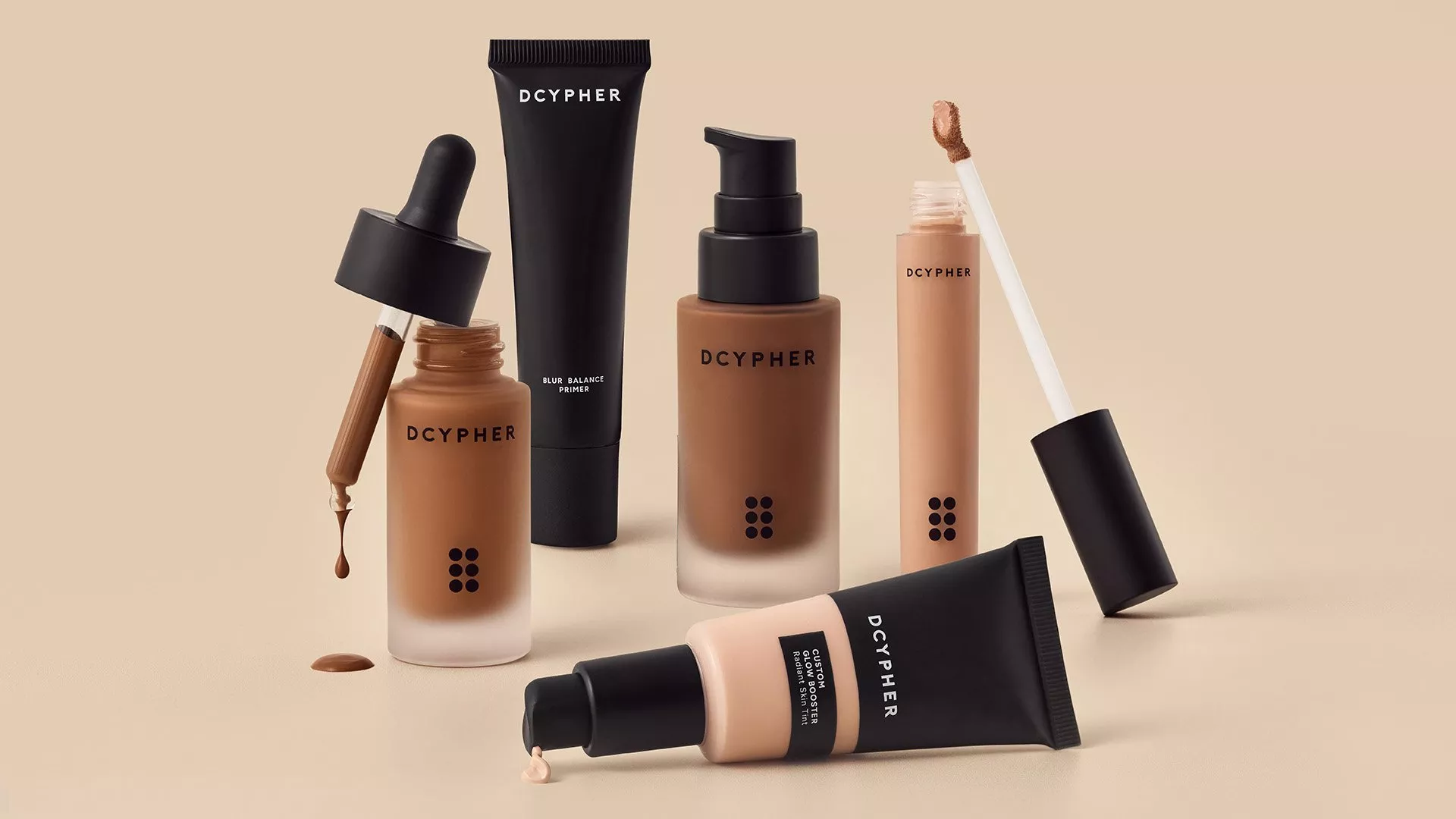 DCYPHER foundation, concealer and primer makeup set in nude tones, with droppers and applicator on beige background