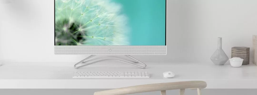 Minimalist home office desk with HP all-in-one desktop PC, keyboard and mouse on white workspace